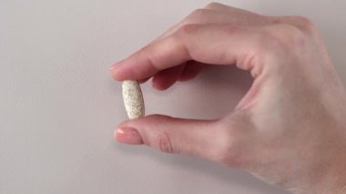 Bej arka planda bir kadının elinde benekler olan büyük bej bir tablet. Kompleks vitamin takviyesi. Yakın plan..