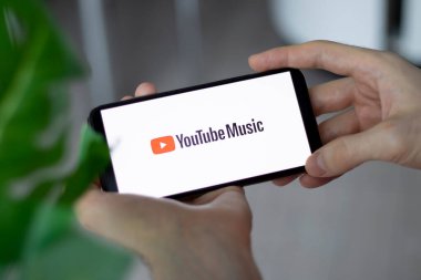 IRPEN, UKRAINE - JANUARY 20 20223, Closeup of smartphone screen YouTube Music logo lettering with in mans hands, Illustrative Editorial