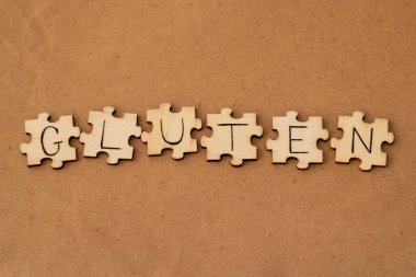 The word gluten on puzzles on a brown background.