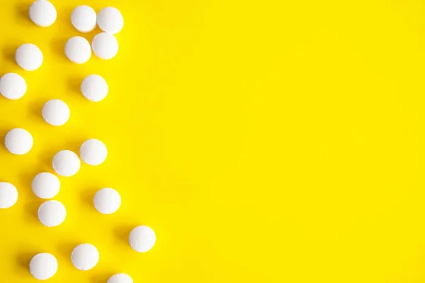 A frame made of tablets. Yellow background with white round tablets, additives on the side. Design for text. Directly Above View