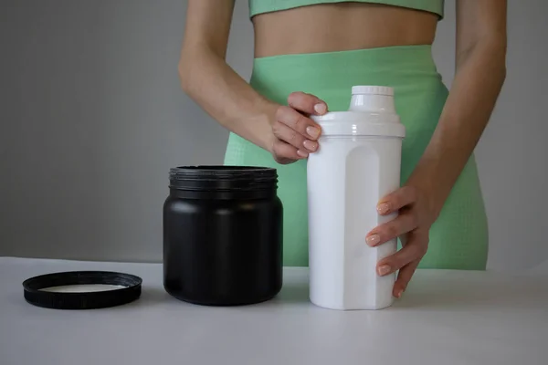 İnce ve genç bir kadın spor için milkshake hazırlıyor.