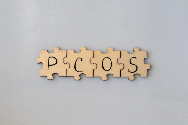 stock image Polycystic Ovarian Syndrome. Hand Writing PCOS on wooden puzzles on a blue background.