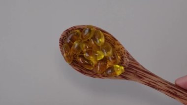 Wooden spoon with yellow capsules of oregano oil supplement. Natural antibiotic.