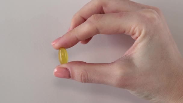 女性の手でオレガノ油サプリメントの黄色のカプセル — ストック動画
