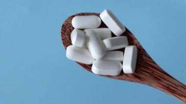 Magnesium Tablets. Magnesium Tablets. White pills, supplements with rounded edges in a wooden spoon on a blue background