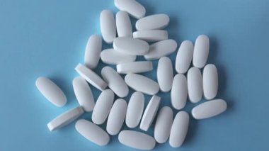 Llutamin beyaz oval tabletler mavi arka plana saçılmış. Uzayı metin için kopyala. Düz yatış, üst görünüm