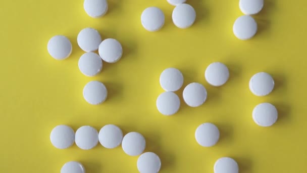 黄色の背景の白い丸い錠剤 トップビュー — ストック動画