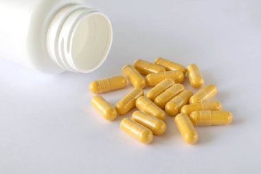Vitamin Coenzyme Q10 on the white background next to the lying jar of supplements. To prevent aging. Pills and medicines.