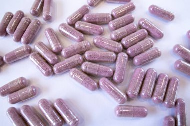 Pink capsules with additives on a white background. Pills and medicines. Tart cherry additives, vitamins, minerals, plant extracts and other beneficial substances.