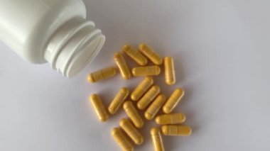 Vitamin Coenzyme Q10 on the white background next to the lying jar of supplements. To prevent aging. Pills and medicines.