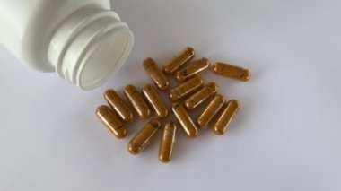 Vitamin curcumin, turmeric in capsules on a white background next to the lying jar of supplements. Pills and medications.