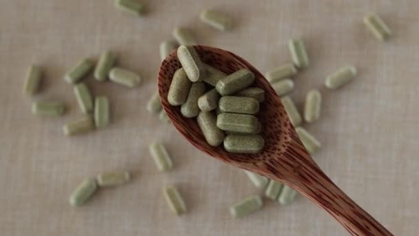 用米色背景的木制勺子把西兰花中的黄花素放在胶囊中制成维生素 绿片和绿药 — 图库视频影像