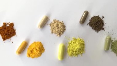 Açıldı ve beyaz arka planda beslenme takviyeleri var. Çeşitli haplar ve vitaminler. Sağ üstten sola: curcumin, Coenzyme q10, C vitamini, quercetin, karınca ağacı kabuğu, vitgrass.