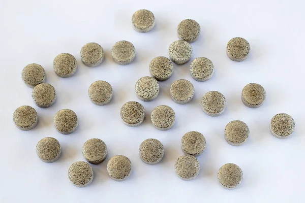Vitamin supplements. Lots of round iron tablets on white background