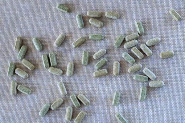 Lots of green yellow pills on a beige background. Supplements, vitamins, medicines or pills. Dietary supplement broccoli