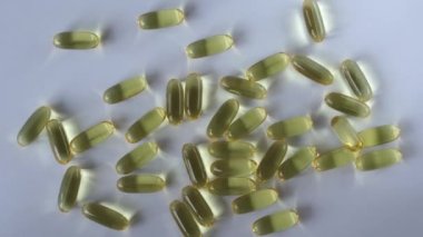 Omega 3 balık yağı kapsülleri beyaz bir zemin ile dağılmış. Üst görünüm