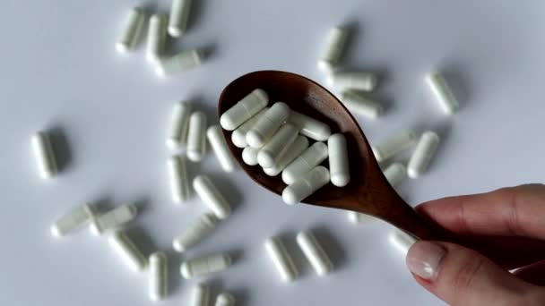 木製のスプーンの白い背景にたくさんの丸薬 ビタミン 薬または錠剤と栄養補助食品 — ストック動画