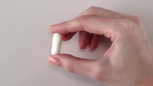 白胶囊一种白色的大胶囊 在妇女的手上有一个补充剂 与白色背景相对应药丸 药物和维生素 — 图库视频影像