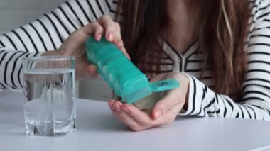 Dişi ilaç kutusundan ilacını alıyor. Dişi ilacını bir bardak suyla içer. Sağlık, sağlık ve ilaç konsepti