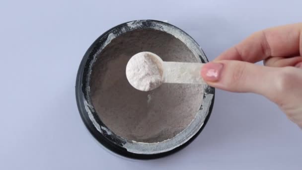 用电解质测量妇女勺子的黑色罐子 手放白色背景 顶视图 — 图库视频影像