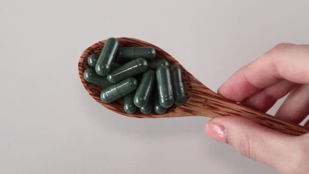 含有叶绿素或螺旋藻的绿色胶囊 在白色背景的木制勺子中加入有用的补充剂或药物 后续行动 — 图库视频影像
