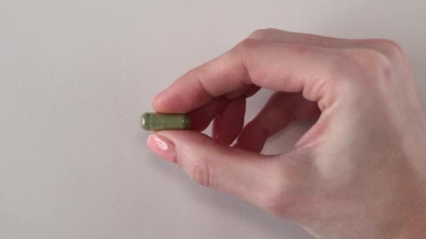 一个绿色的草药胶囊在一个女人的手里 补充剂和药物使你保持健康 — 图库视频影像