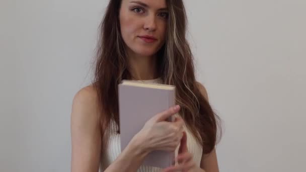 美しい幸せな若い女性は彼女の手にベージュの本を保持し それを開きます — ストック動画