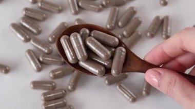 Kahverengi Vitgrass kapsülleri bej bir arka planda, tahta bir kaşıkta. İlaçlar, ilaçlar ve haplar. Yakın plan..