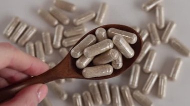 Bej rengi sağlık vitamini kapsülleri tahta bir kaşıkta bej bir arka planda yayılıyor. Beslenme takviyeleri.