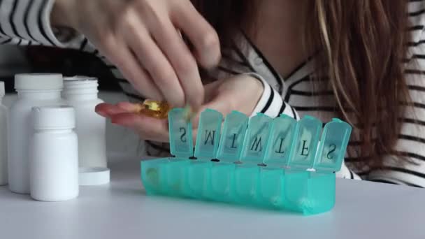 Egy Halolaj Kapszulát Tesz Gyógyszer Szervező Minden Sejtjébe Tabletta Doboz — Stock videók