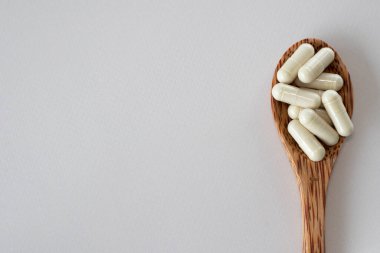 Tahta kaşıkta duran bej kapsüller yan tarafta. Alerji takviyeleri ve ilaçlar. Metin için tasarım. Doğrudan Görünümün Üzerinde
