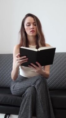 Sıska kadın oturur ve bir kağıt kitap okur. Okumanın Yararları. Okumak hayatınızı nasıl geliştirebilir? Dikey Video.