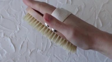 Body brush for dry massage in womens hands. Brushing body to reduce cellulite, detoxify the lymphatic system, and achieve beautiful smooth skin. Body treatment after shower.