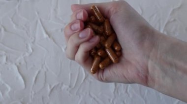 Bir kadının elinde turuncu zerdeçal ya da curkimin vitamin takviyeleri, yakın plan..