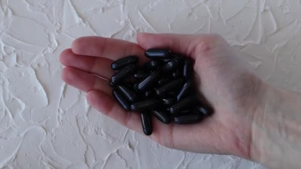 黑激活椰子木炭胶囊在一个女人的手中 健康与健康 自行用药 — 图库视频影像