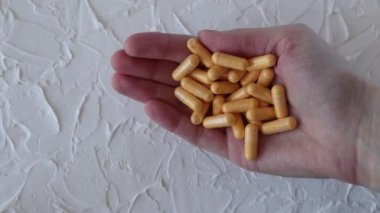 Sarı ilaçlar ya da takviyeler, bir kadının elindeki Q10 koenzim kapsülleri..