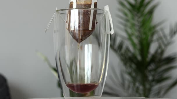 朝のコーヒードリップを二重底のクリアカップにフィルターバッグで醸造するプロセス — ストック動画
