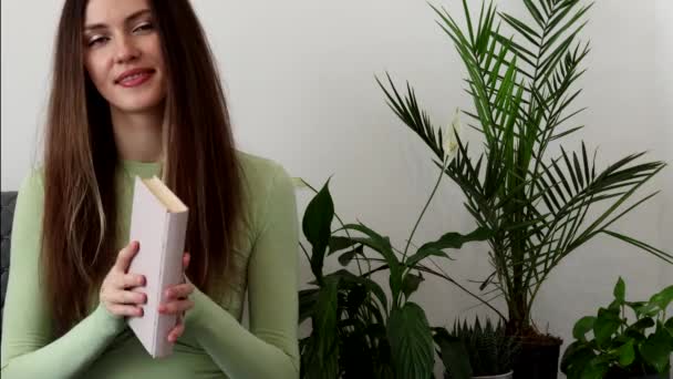 長い髪と彼女の手の中に本を持つ幸せな 美しい若い女性 写真の緑の色調 — ストック動画