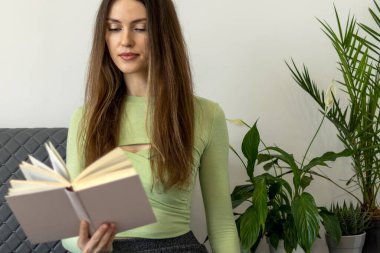 Uzun saçlı ve elinde kitap olan mutlu, güzel bir genç kadın..