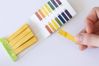 Su pH ölçüm testi. Sarı şerit bir kadının elinde.