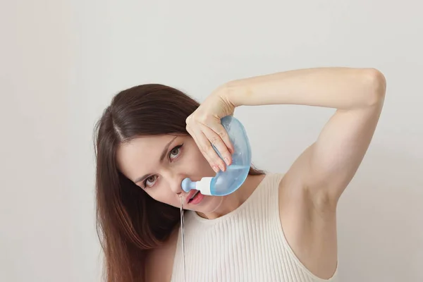 Nasal irrigation. A young woman uses the Neti Pot to treat her runny nose and colds. Nasal lavage, irrigation therapy