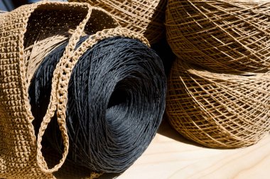 Raffia 'nın topları tahtaya yakın çekim yapıyor. Siyah ve bej rafya derileri örgü örmeye hazır..