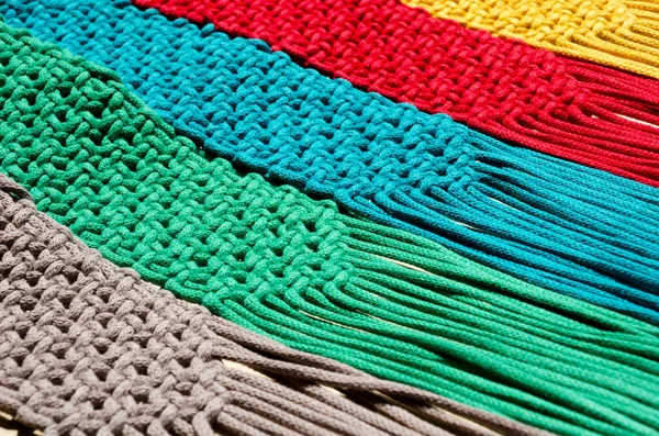 stock image Macrame technique, a square knot of multi-colored threads. Colored macrame stripes in blue, yellow, red, beige, green and pink colors.