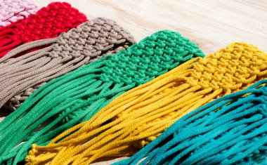 Makrome tekniğiyle örülmüş küçük el çantaları. Ahşap bir arka planda çok renkli cep telefonu çantaları.