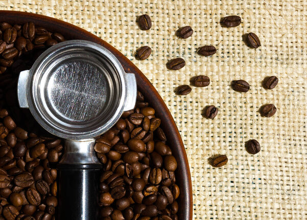 Selected Arabica coffee beans. A coffee cone and coffee beans lie on a ceramic plate against a background of burlap.