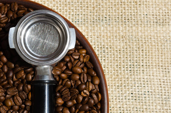 Selected Arabica coffee beans. A coffee cone and coffee beans lie on a ceramic plate against a background of burlap.