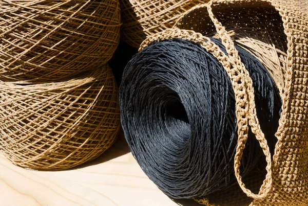 stock image Skeins of raffia and a women's bag. Rolls of beige and black raffia are ready to be knitted.