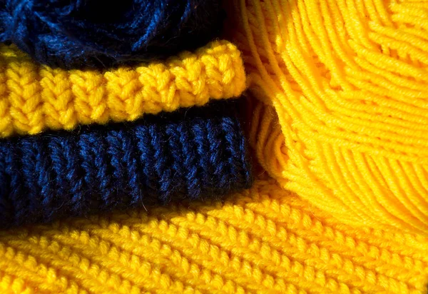 Texture of a crochet pattern made from yellow and blue wool yarn. Close-up sample of the pattern.
