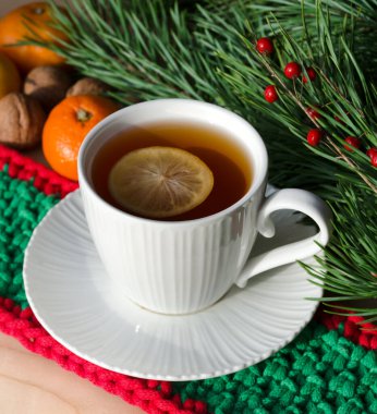 Mandalinalar, fındıklar ve bir bardak limonlu sabah çayı bir Noel ağacının yeşil dallarının arka planında. Yeni yıl ve Noel için süslemeler. Tebrikler için bir yer..