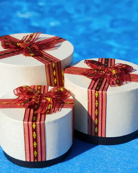 Three gift boxes on a background of a swimming pool. Gifts tied with ribbons. Place for text.